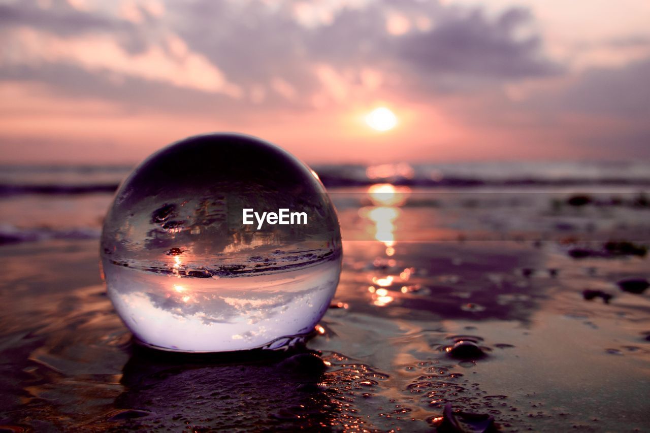 reflection, sunset, sky, water, sea, nature, land, cloud, beach, sunlight, sphere, dusk, light, beauty in nature, tranquility, no people, scenics - nature, environment, horizon, outdoors, horizon over water, evening, sand, focus on foreground, ocean, sun, crystal ball, tranquil scene, travel destinations, travel, twilight, idyllic, macro photography