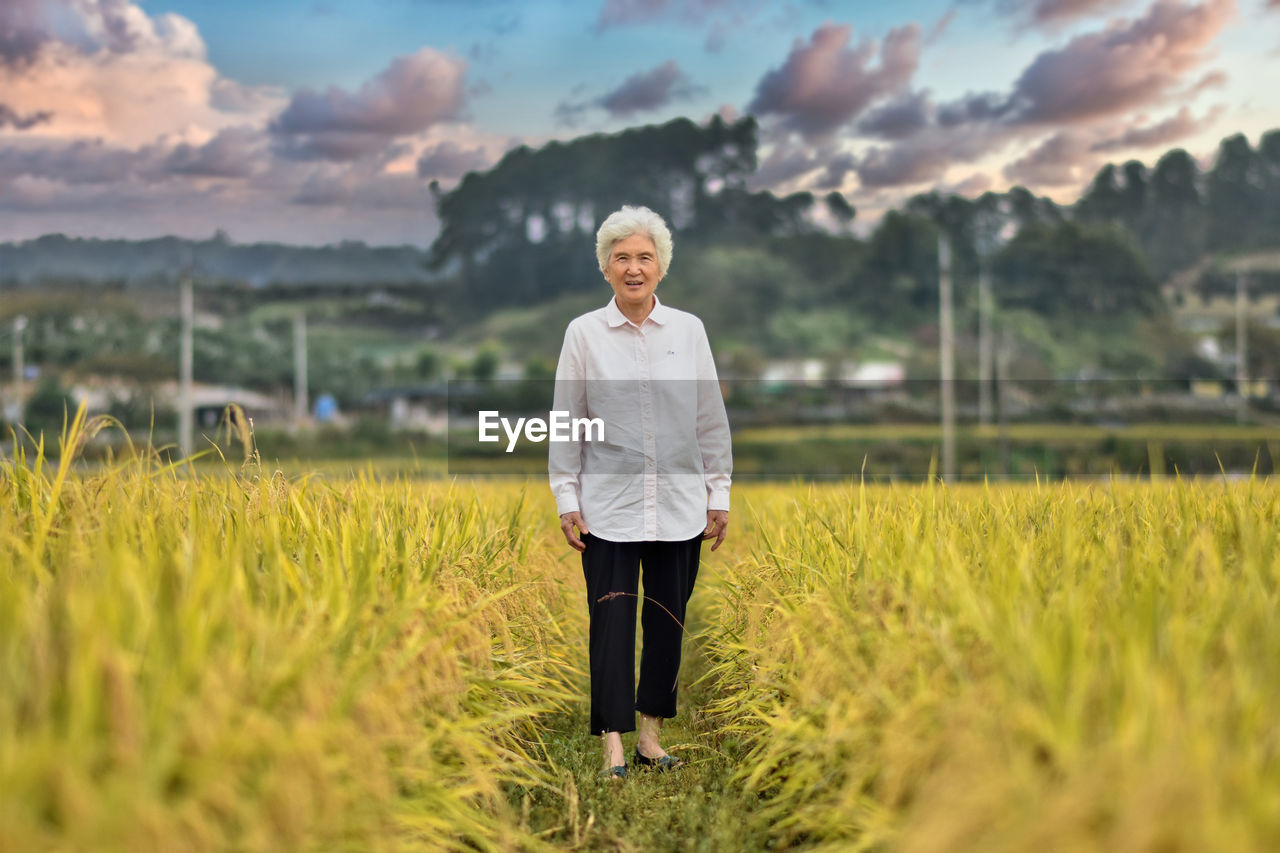 Portrait of smiling old woman standing on field