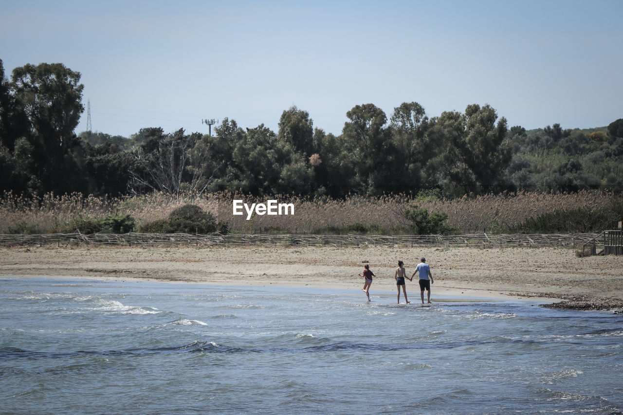 PEOPLE AT BEACH AGAINST SKY