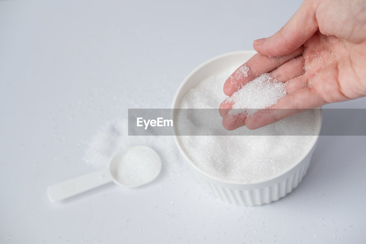 Epsom salt in hand for bath on white background. useful salt for relaxation in the bath. 