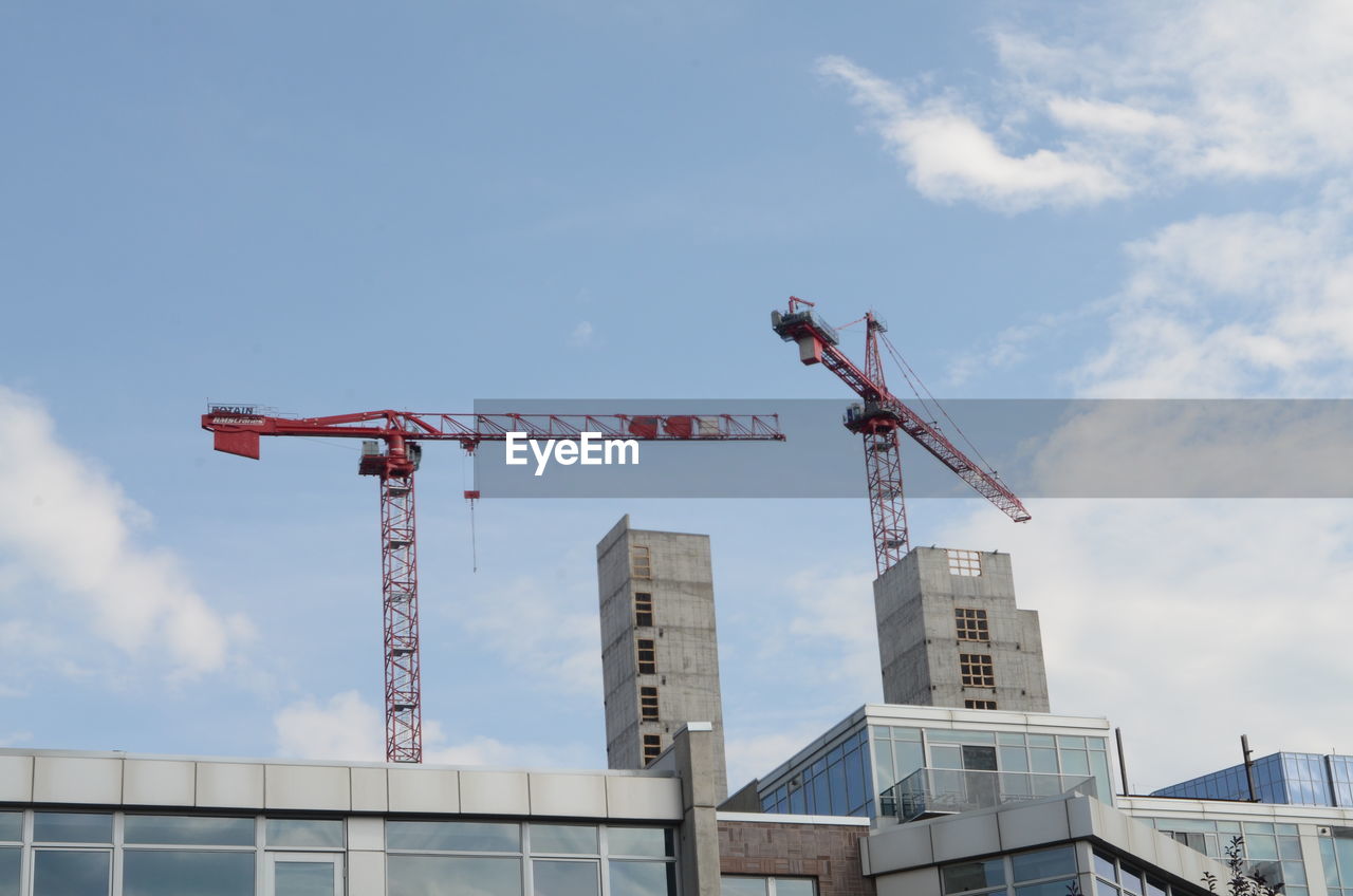 LOW ANGLE VIEW OF CRANES AT CONSTRUCTION SITE