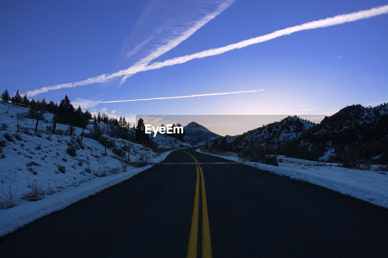 ROAD ALONG SNOW COVERED LANDSCAPE