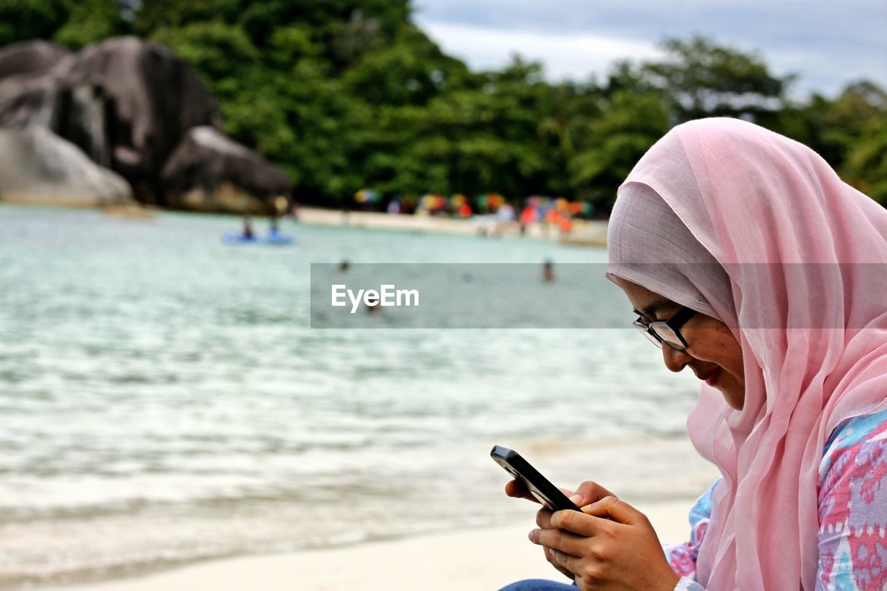 Midsection of woman holding smartphone on beach