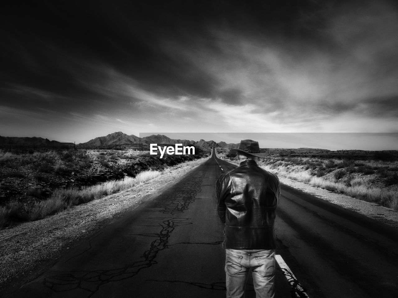 Rear view of man standing on road against sky