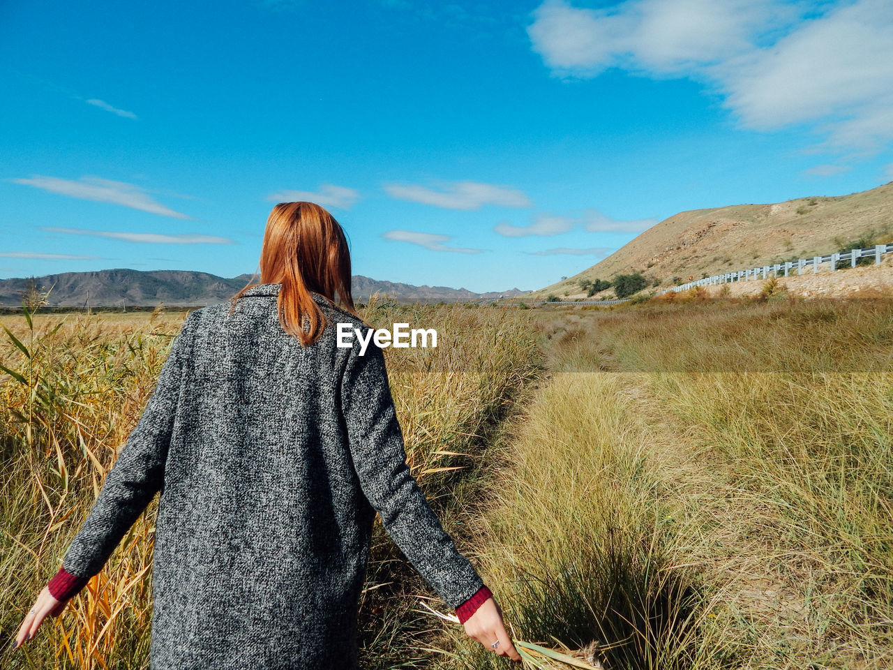 Rear view of woman walking on field against sky