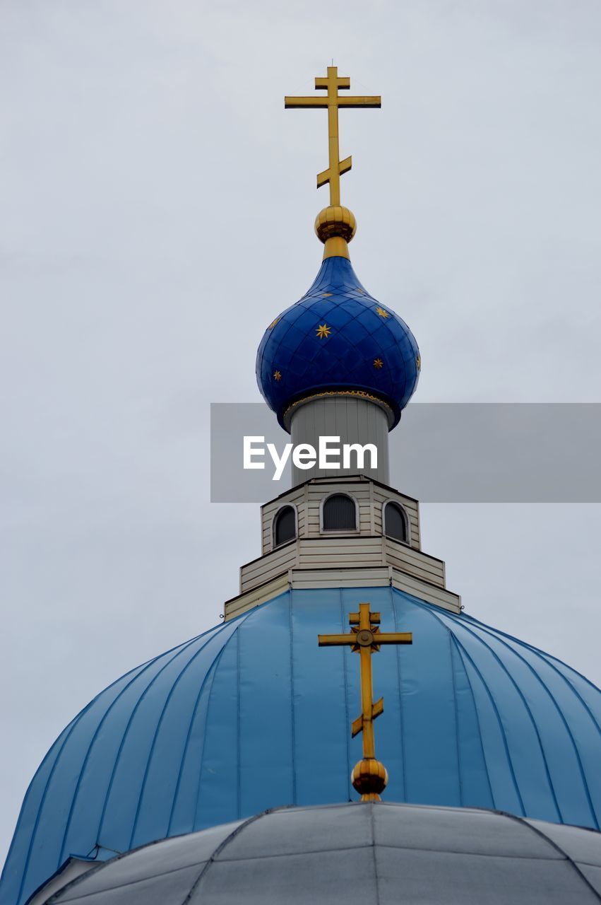 Low angle view of cross by building against sky