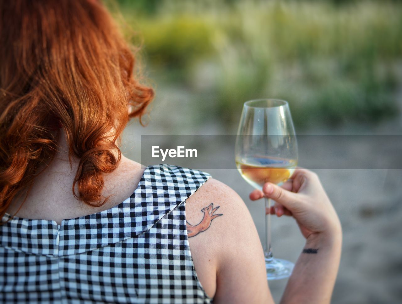 Rear view of woman holding wineglass outdoors