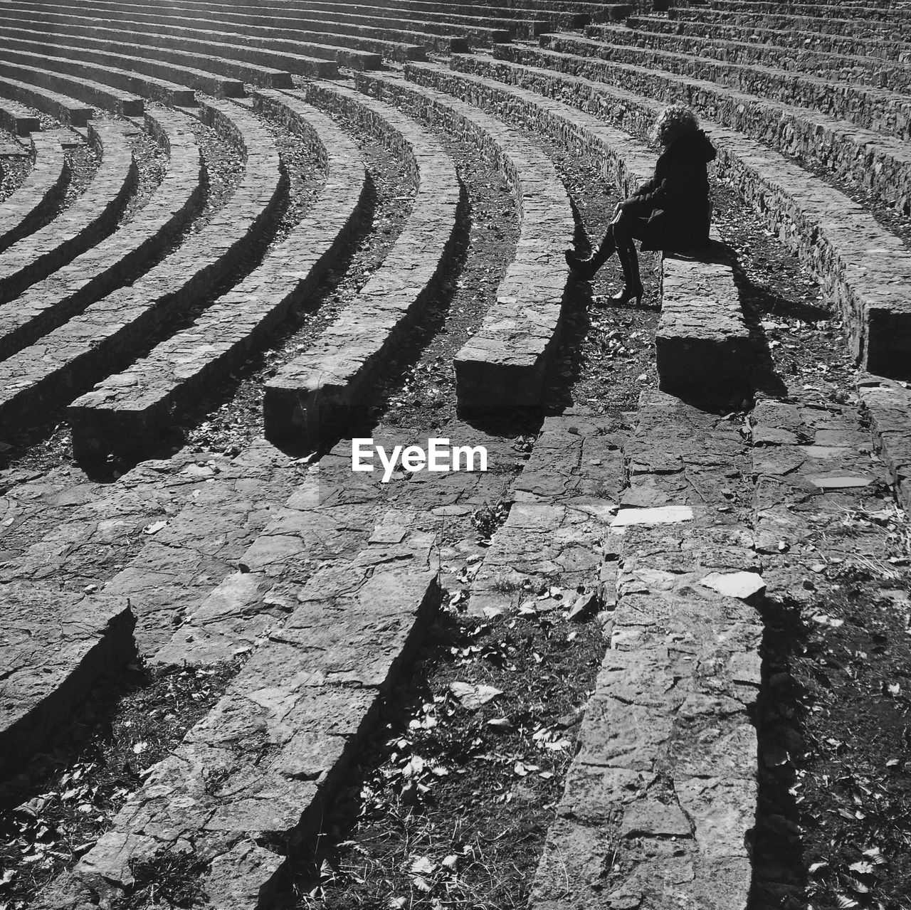 Woman sitting on abandoned amphitheater