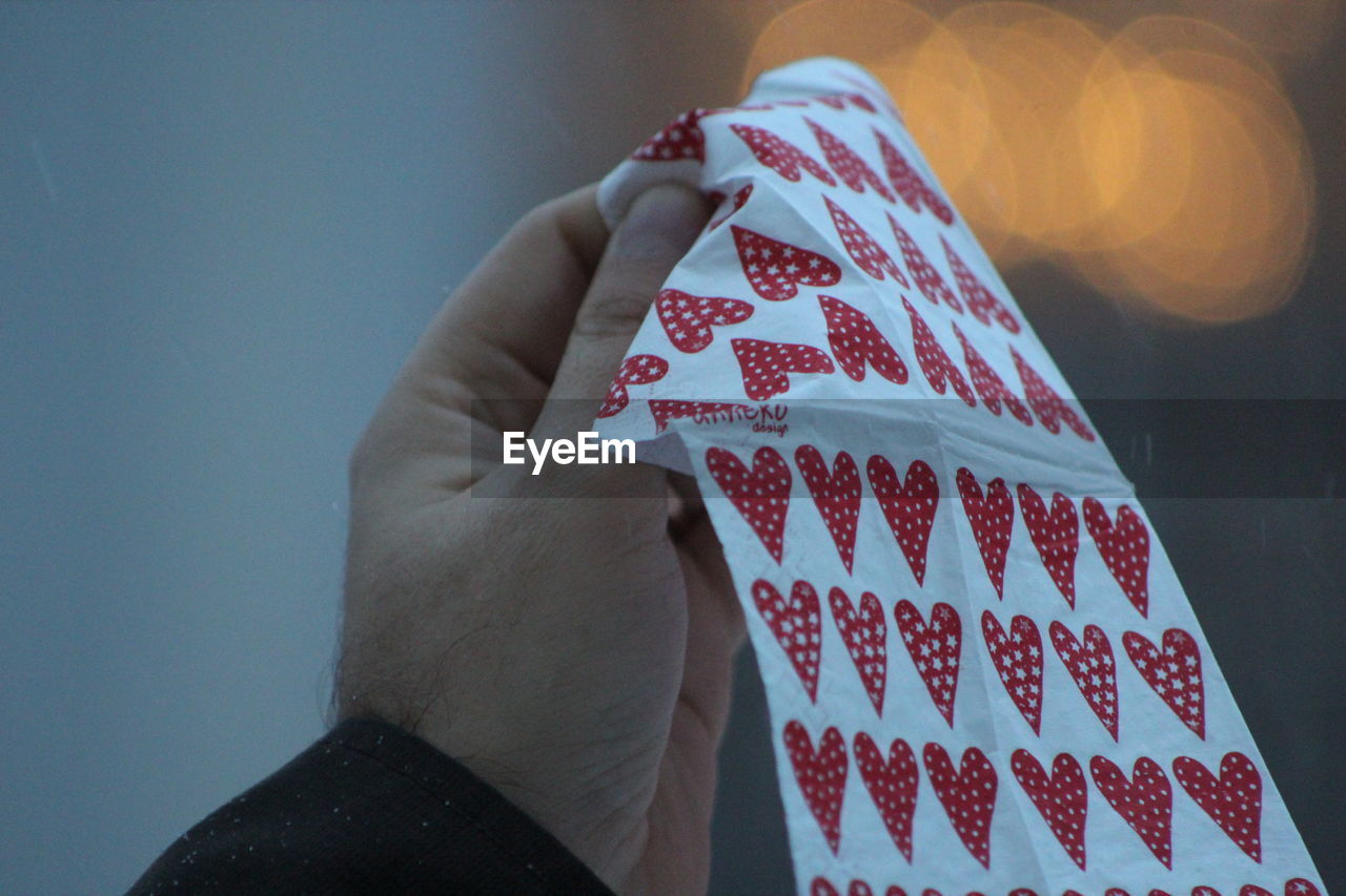 CLOSE-UP OF HAND HOLDING UMBRELLA AGAINST WALL