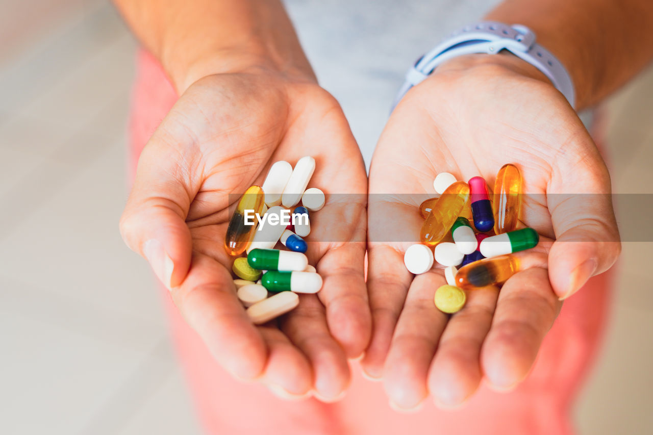 cropped hands of person with pills against white background