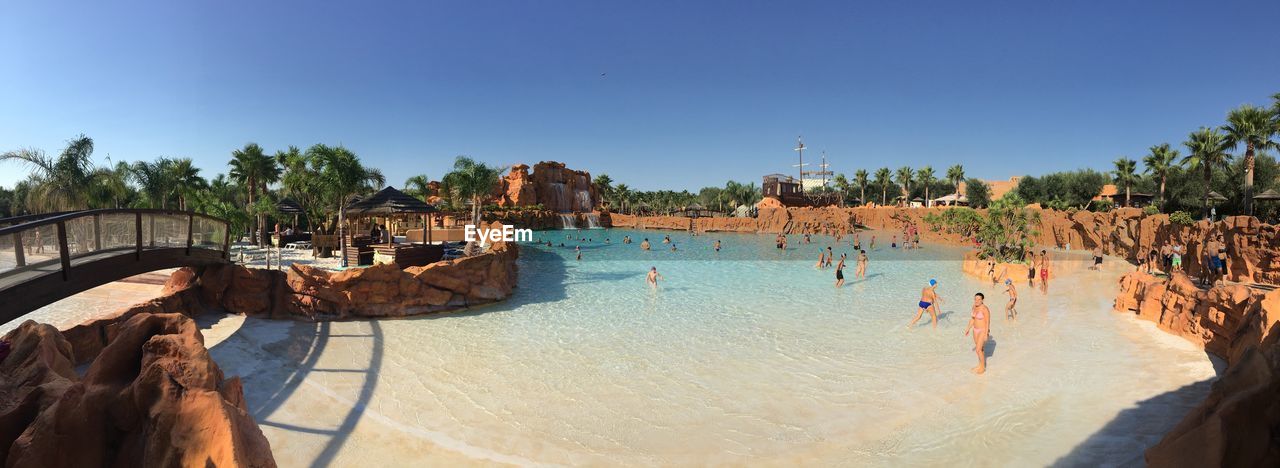 PANORAMIC VIEW OF PEOPLE AT SWIMMING POOL