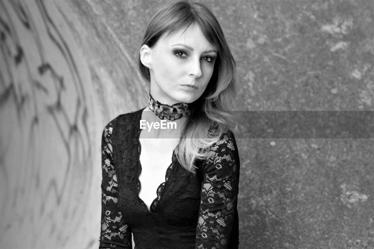 Portrait of woman standing against wall