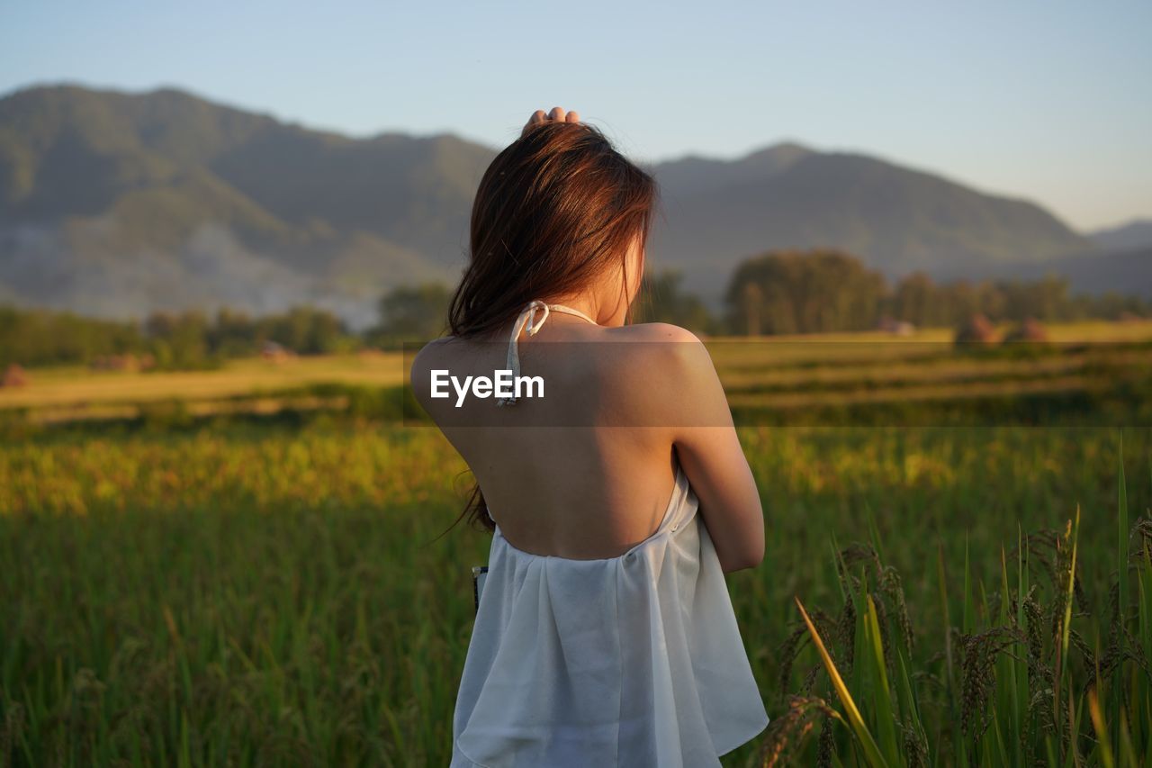 Rear view of fashionable woman standing on field