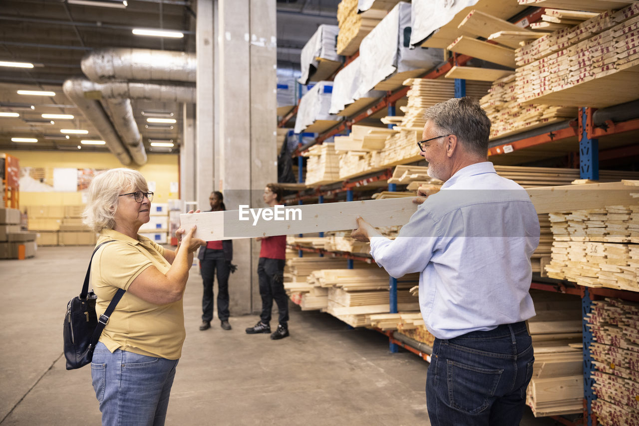 Senior man and woman choosing plank on rack at hardware store