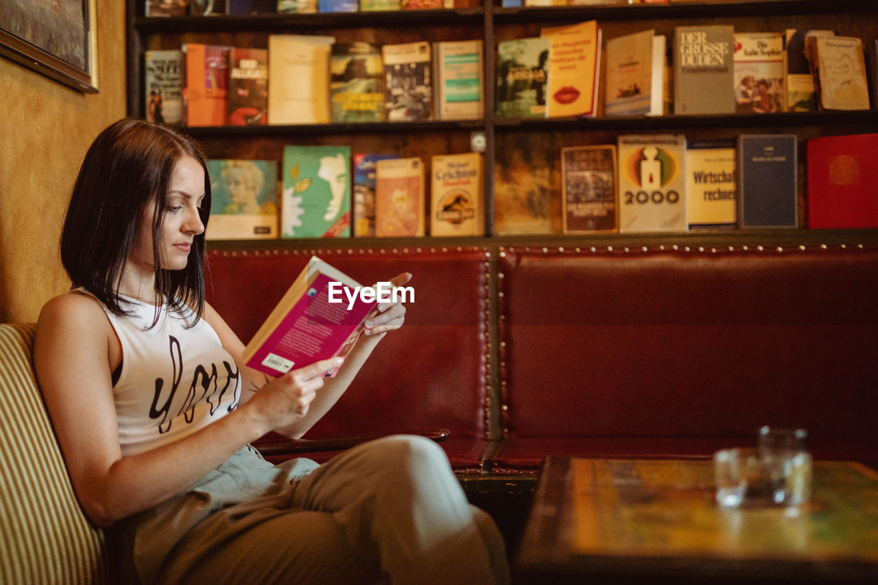 Young woman reading book on sofa