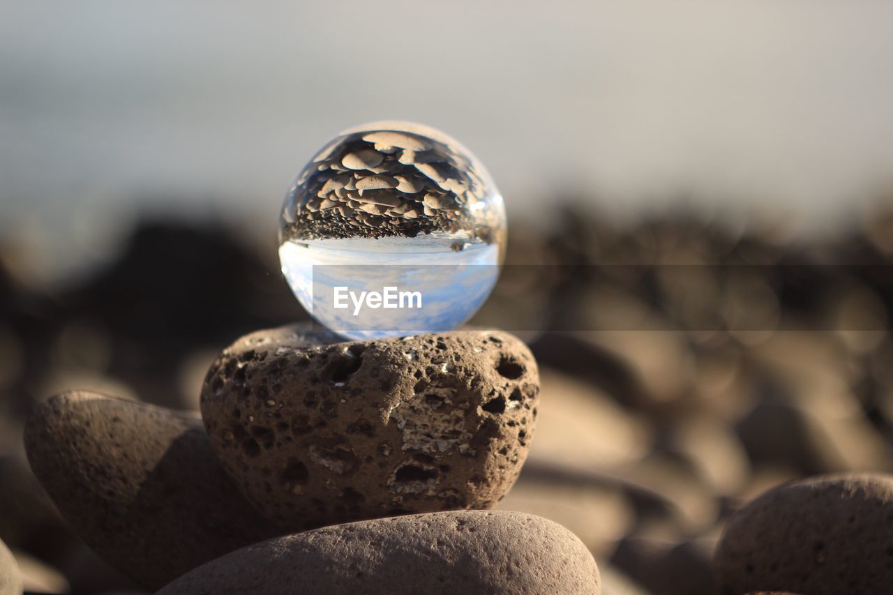 Close-up of crystal ball on pebble at beach