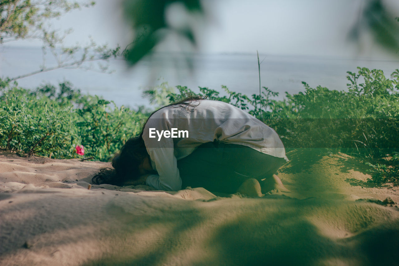 SIDE VIEW OF A MAN LYING ON FIELD