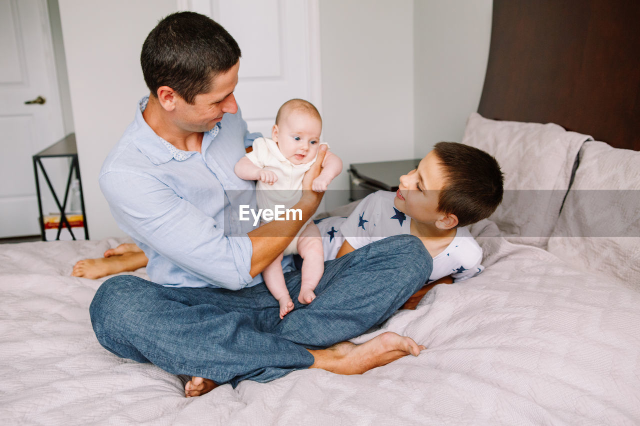 Fathers day holiday. caucasian father dad holding newborn baby. brother playing with sister