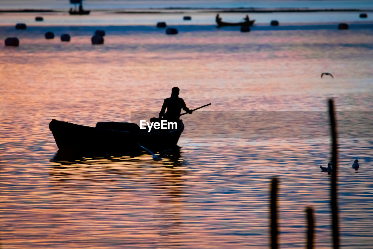 SILHOUETTE MAN ON BOAT AT SEA