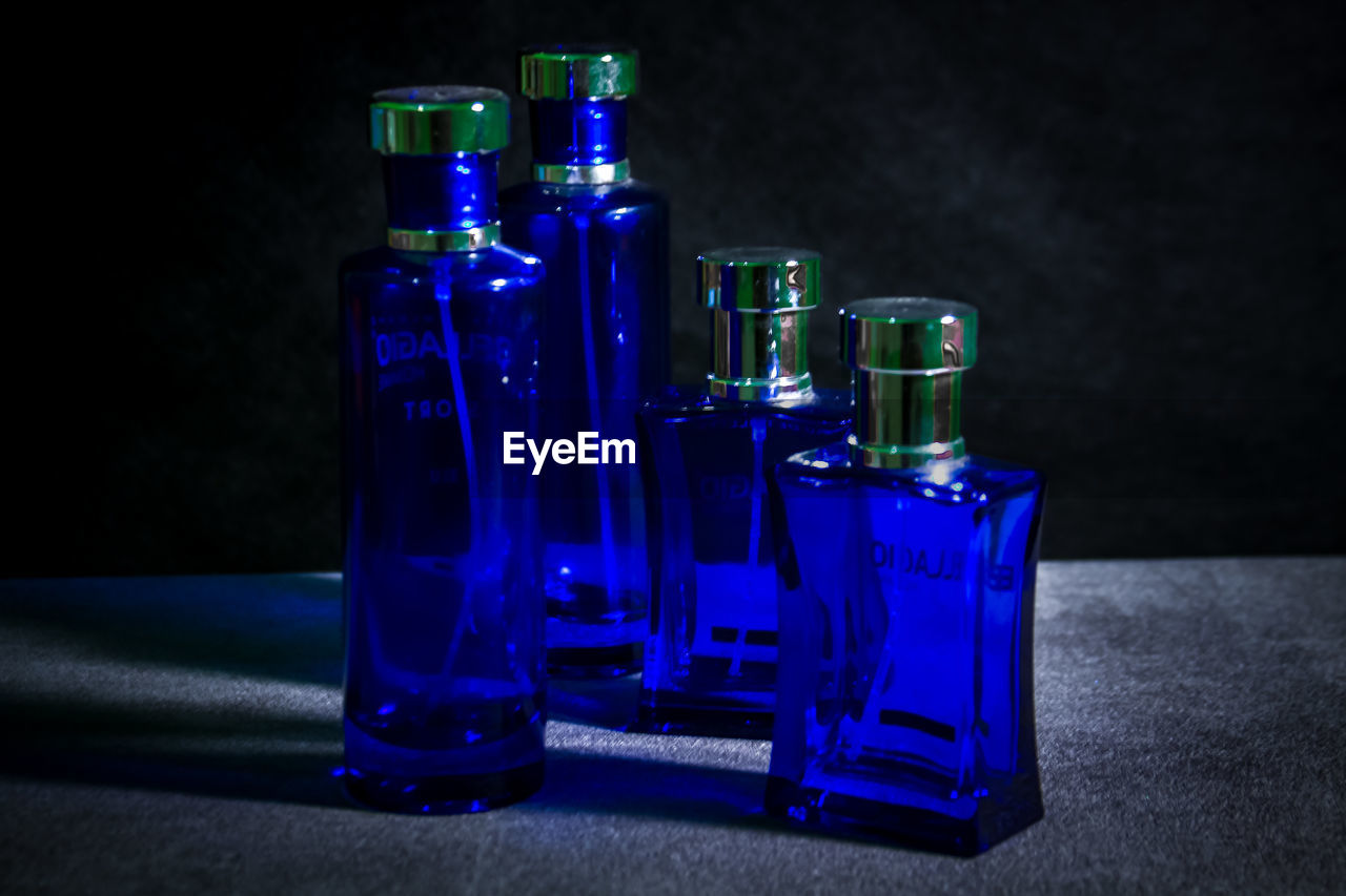 cobalt blue, blue, bottle, container, glass bottle, indoors, glass, no people, perfume, food and drink, studio shot, drink, still life, refreshment, alcohol, group of objects, purple, black background, drinking glass
