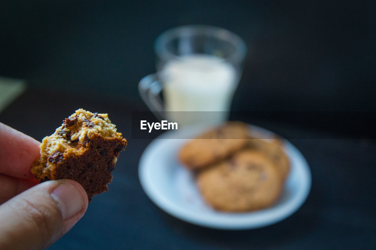 Cropped hand having cookies with milk