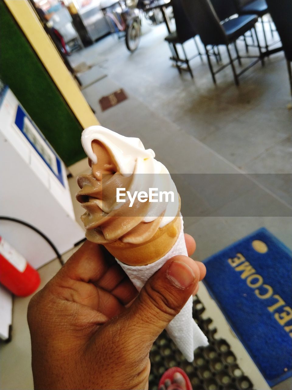 hand, food and drink, ice cream, frozen food, sweet food, food, ice cream cone, cone, sweet, holding, frozen, dairy, dessert, unhealthy eating, one person, temptation, freshness, personal perspective, business, adult, close-up, indoors