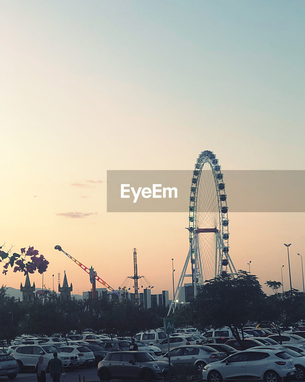 FERRIS WHEEL AGAINST SKY IN CITY DURING SUNSET