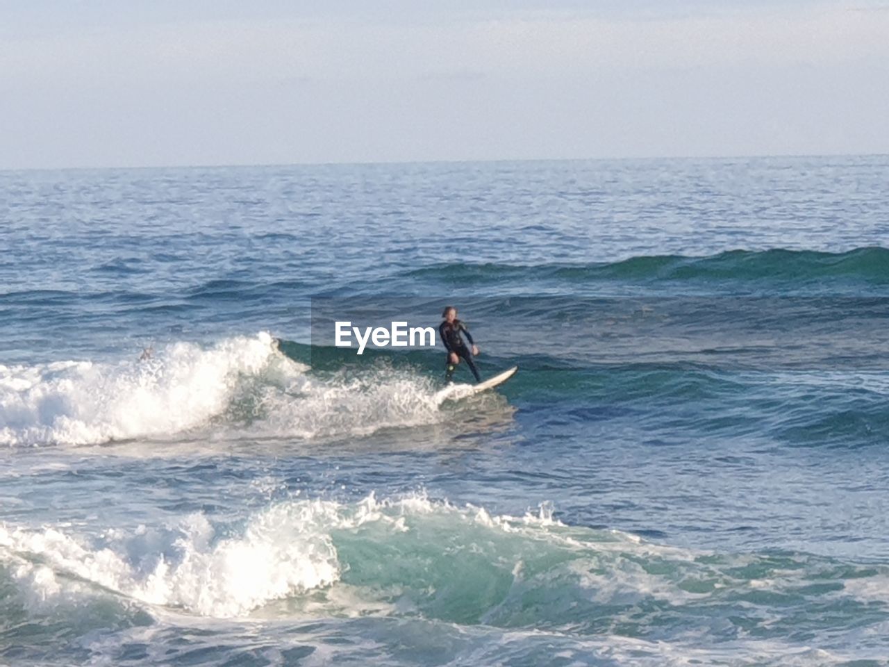 rear view of man surfing in sea against sky