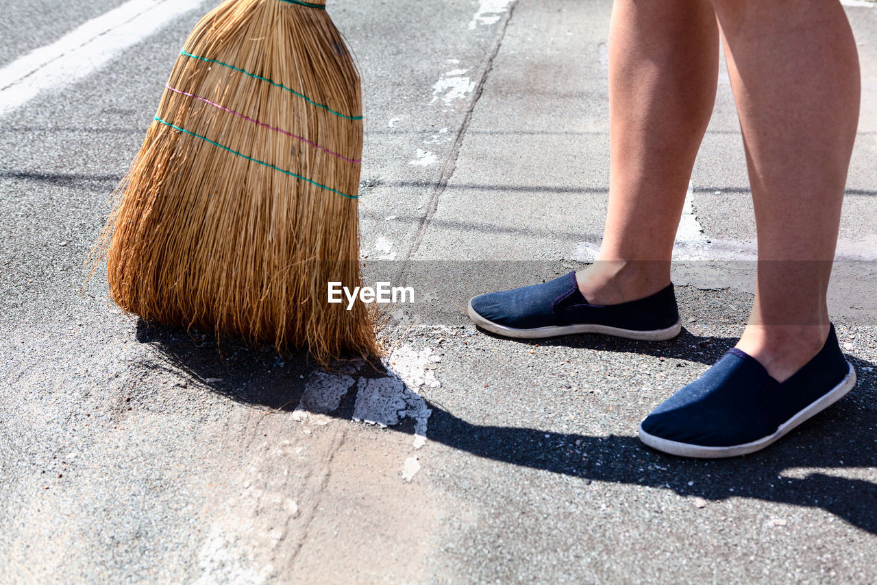 Exterior cleaning with corn broom . courtyard floor sweeping . feet and corn broom