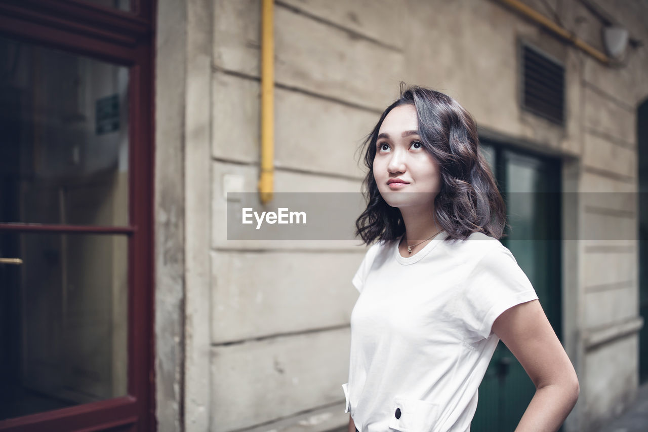 Optimistic asian female student in a white t-shirt, looking up. summer lifestyle portrait