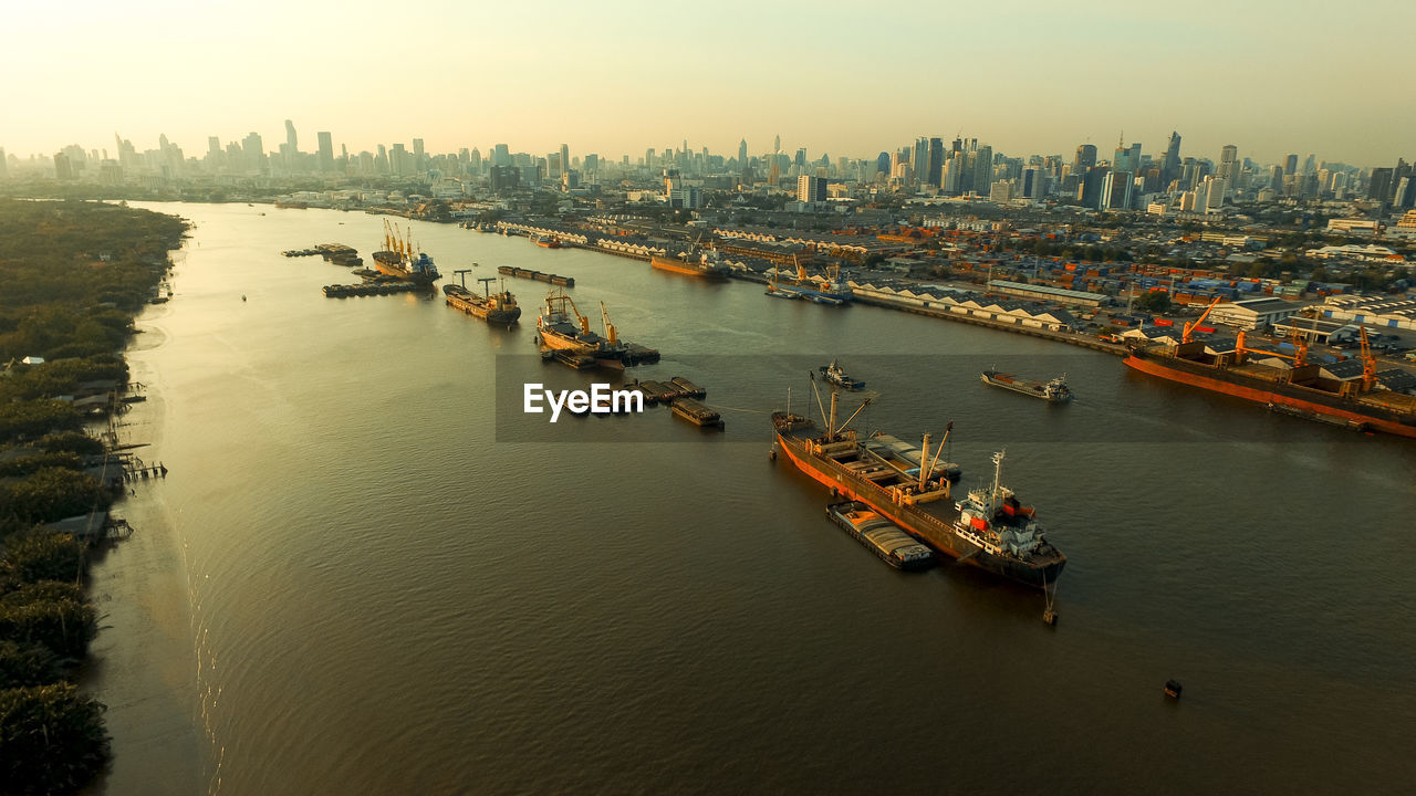 High angle view of boats in river by buildings during sunset