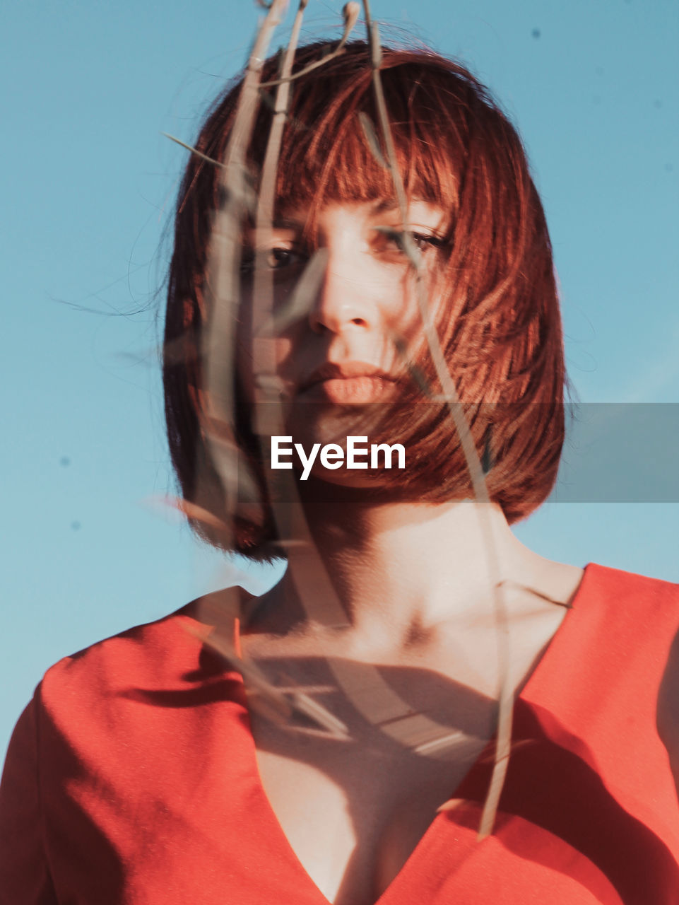 Portrait of young woman standing against sky