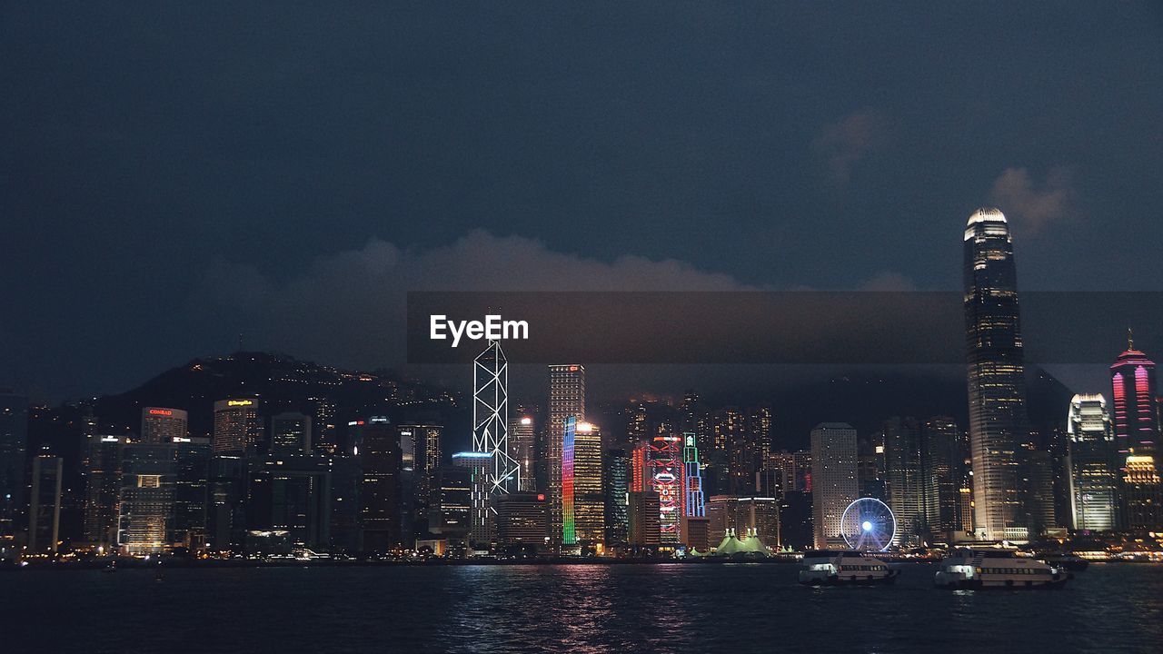 Illuminated buildings in city against sky at night