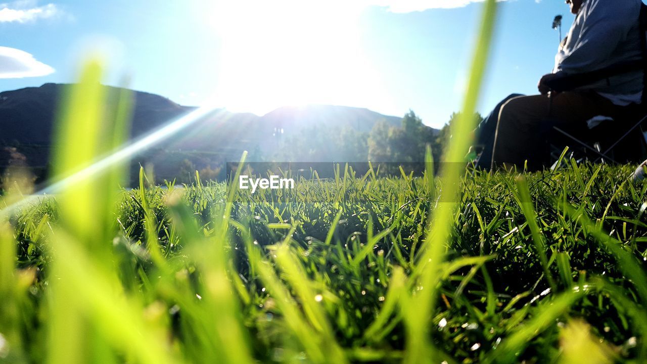 Midsection of man on grassy field against bright sky