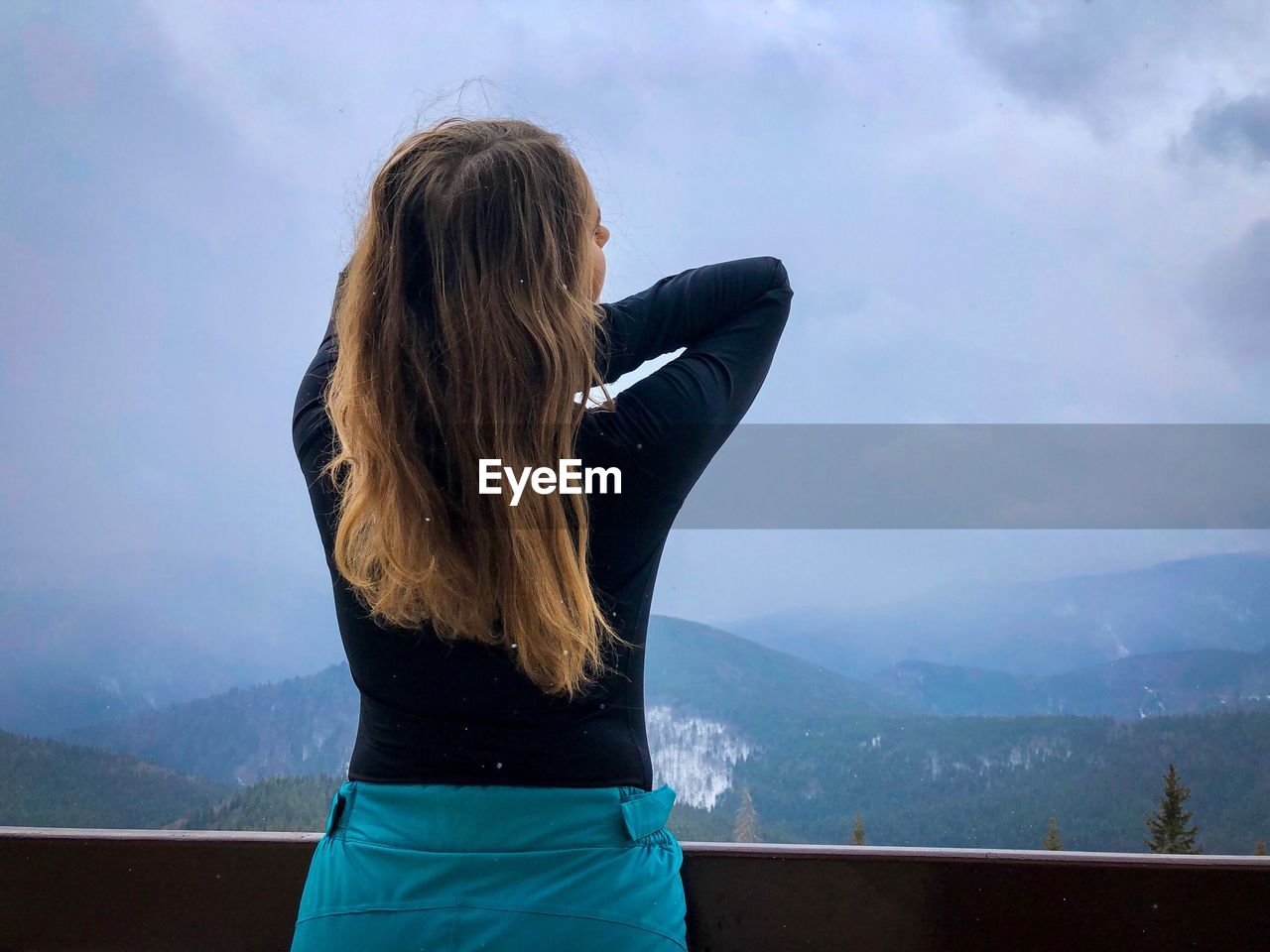 Rear view of woman looking at mountains against sky