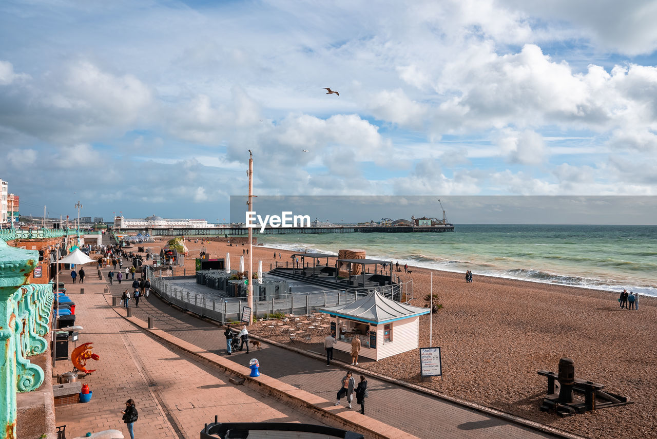 People walking down the promenade near the beach in brighton.