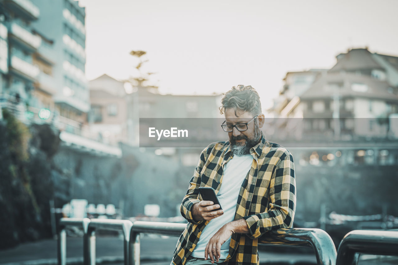 portrait of young man using mobile phone in city