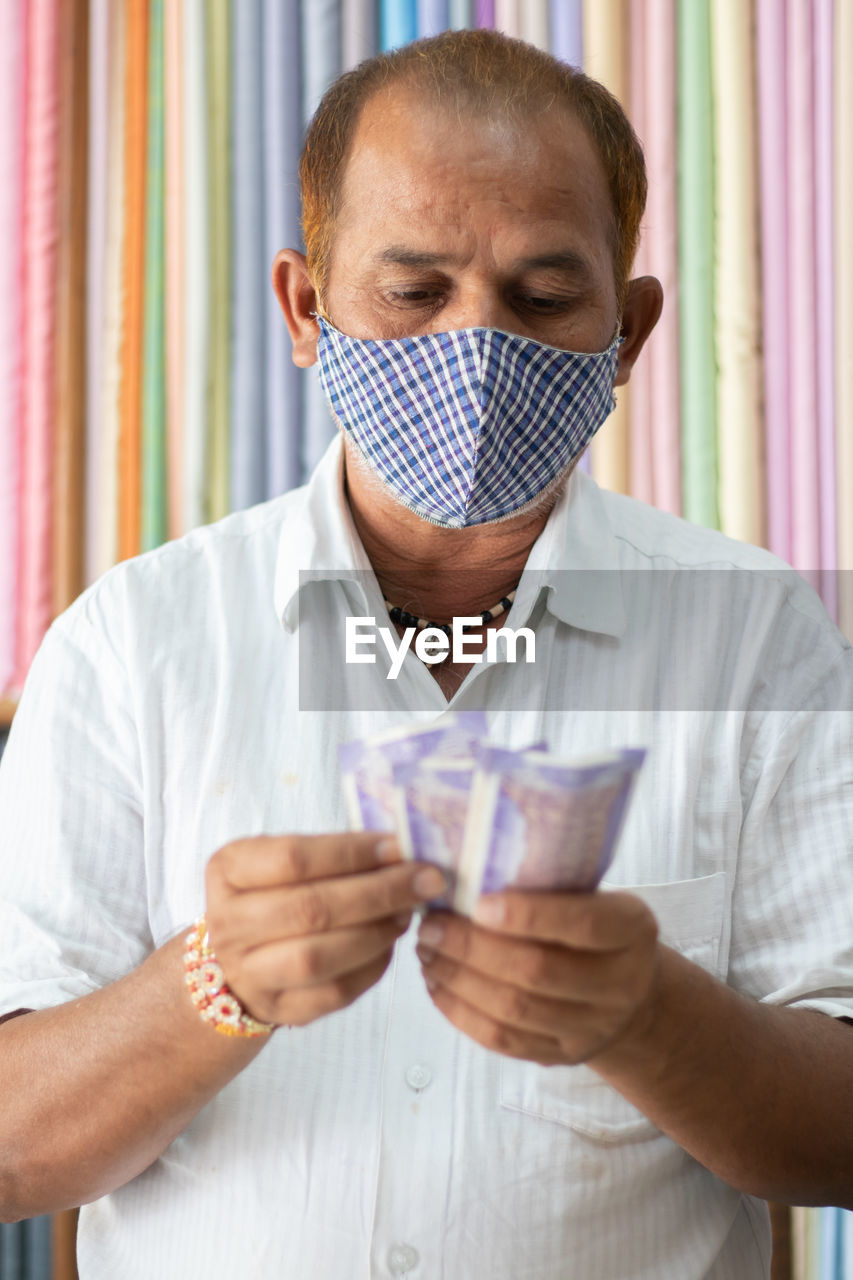 Portrait of man wearing mask and holding currency