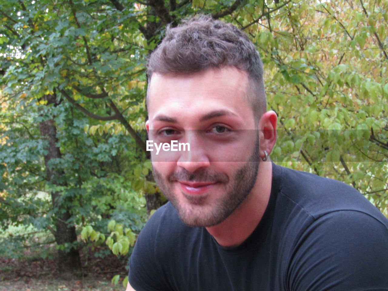 PORTRAIT OF SMILING YOUNG MAN AGAINST PLANTS