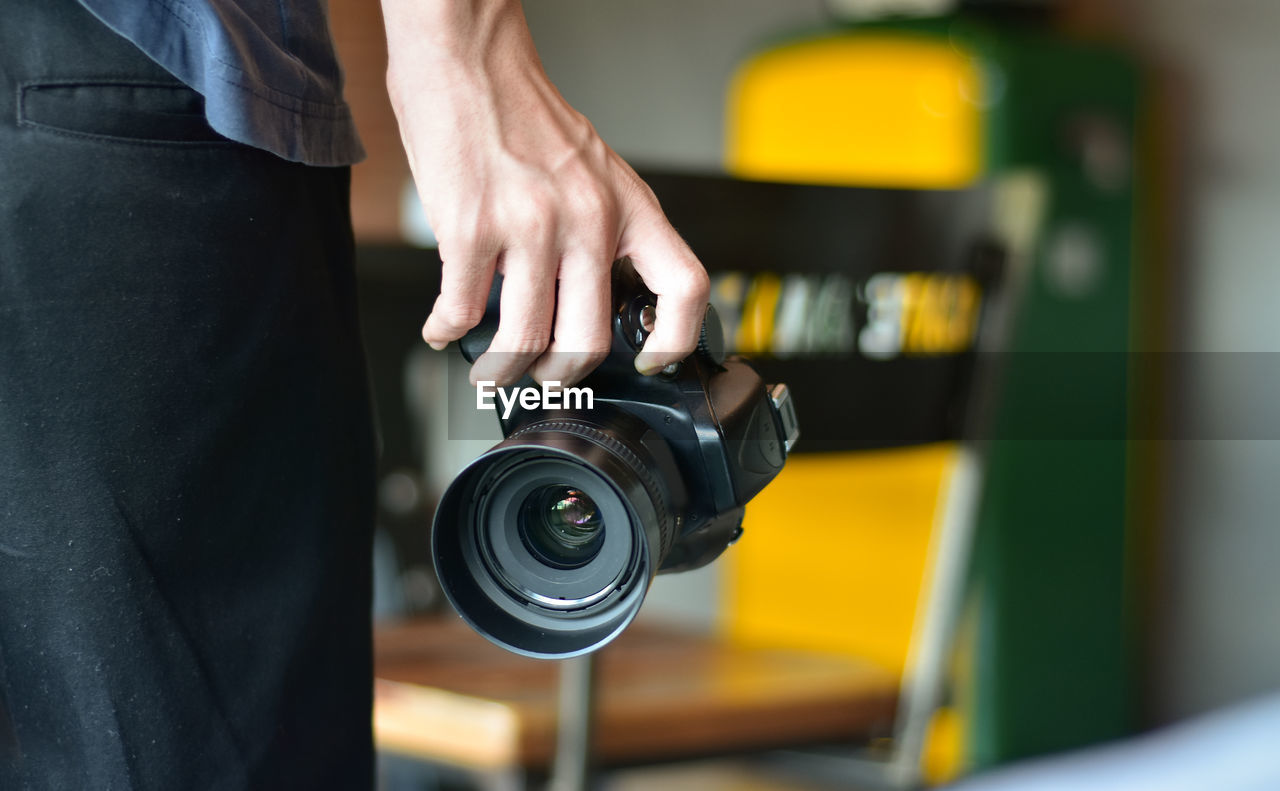 Midsection of man holding camera