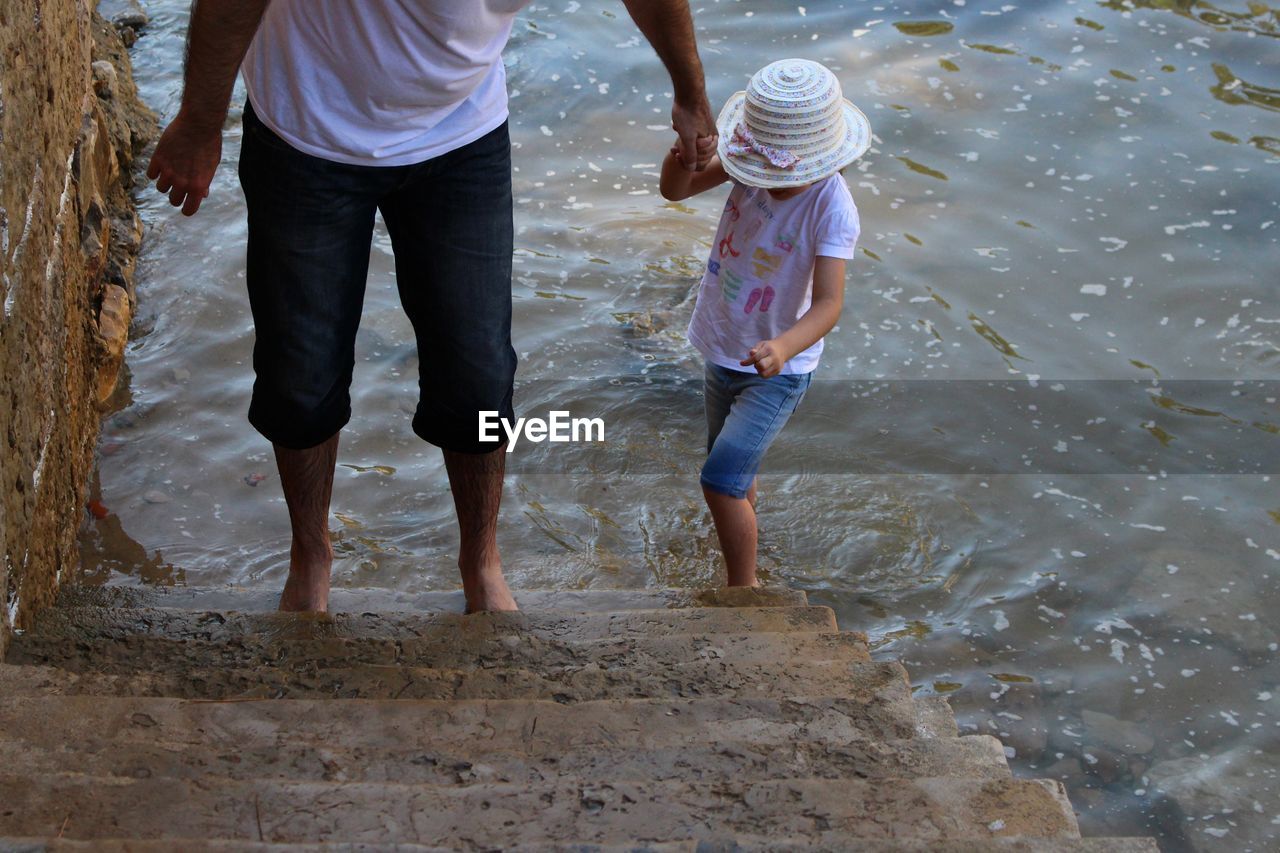 Low section of father helping daughter on steps