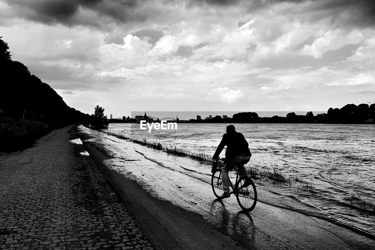 Man riding bicycle through the high water of the river rhine