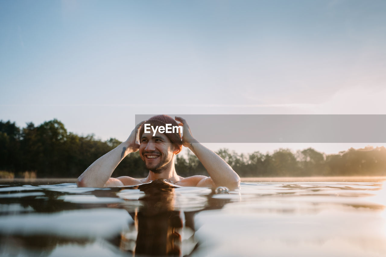 Young man soaks in the winter lake at morning. male person taking care of his health