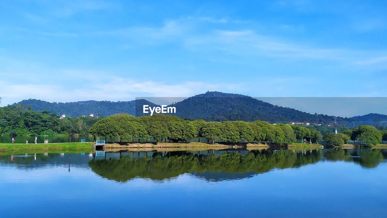 REFLECTION OF TREES IN LAKE AGAINST SKY