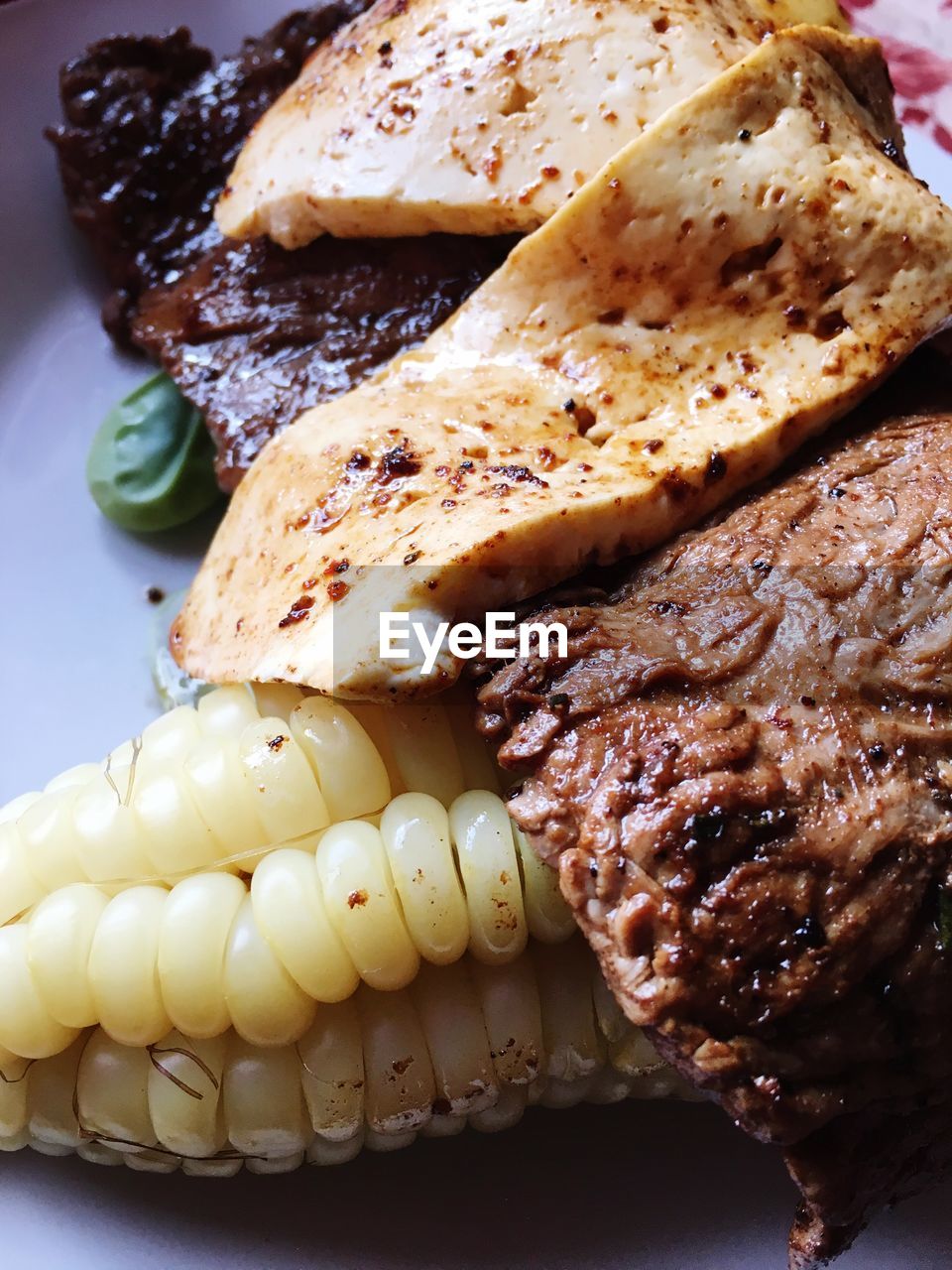 Meat served with maze and cheese on plate