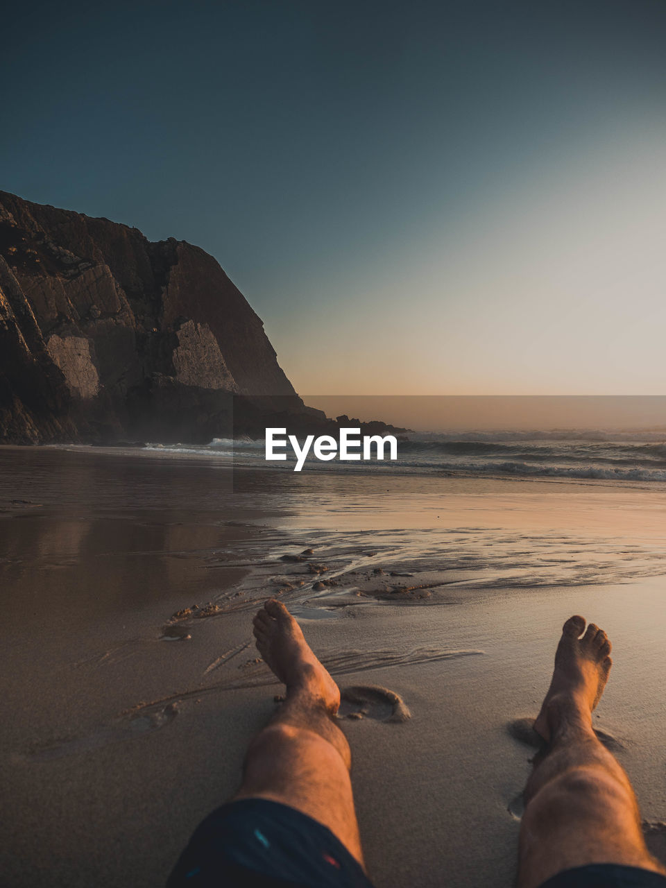 Low section of man on beach against clear sky