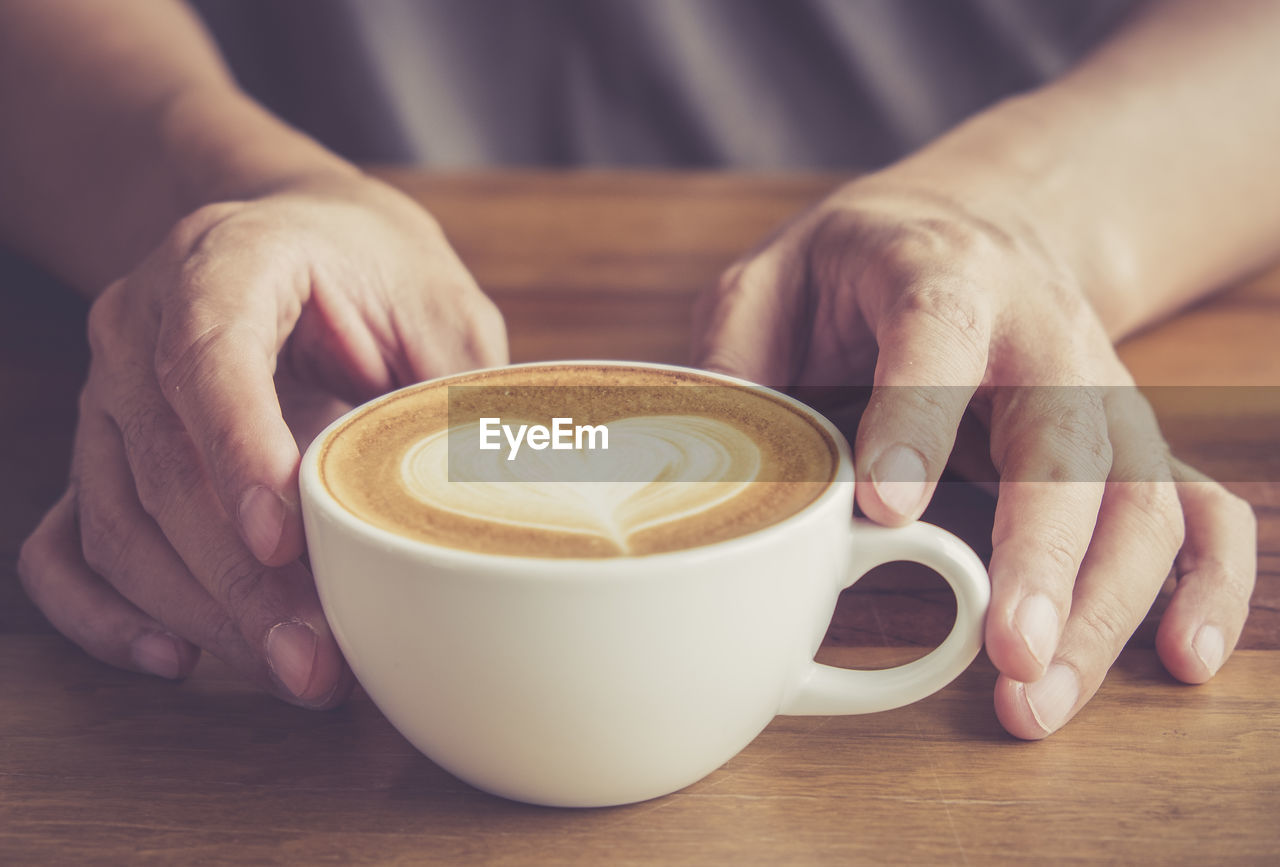 Midsection of woman with coffee cup on table