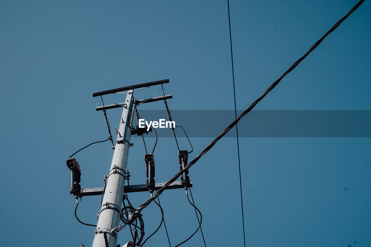 Low angle view of electricity pylon against clear sky