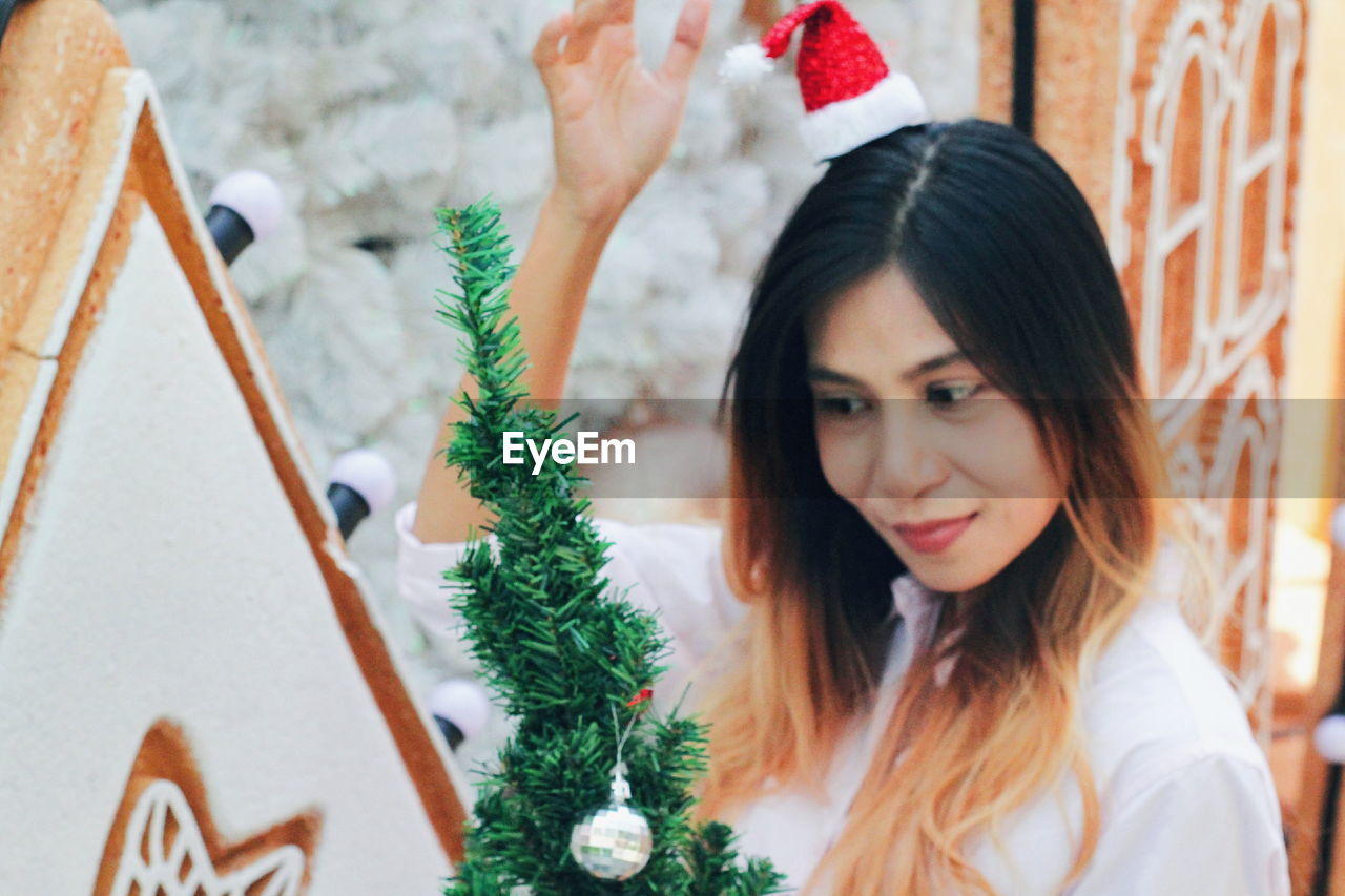 PORTRAIT OF WOMAN WITH CHRISTMAS TREE IN PARK