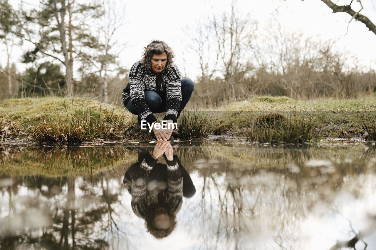 Female explorer washing hands in lake at forest